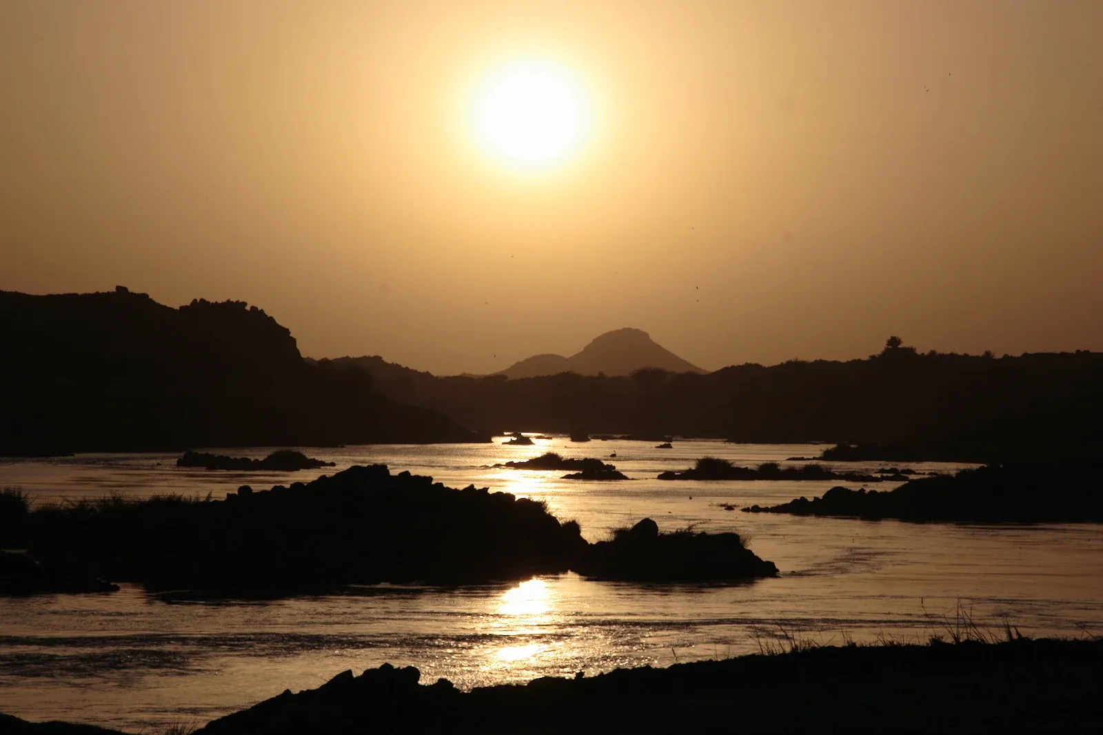 Sunset over the Nile at Dar al-Manasir, rocks silhouetted in the water