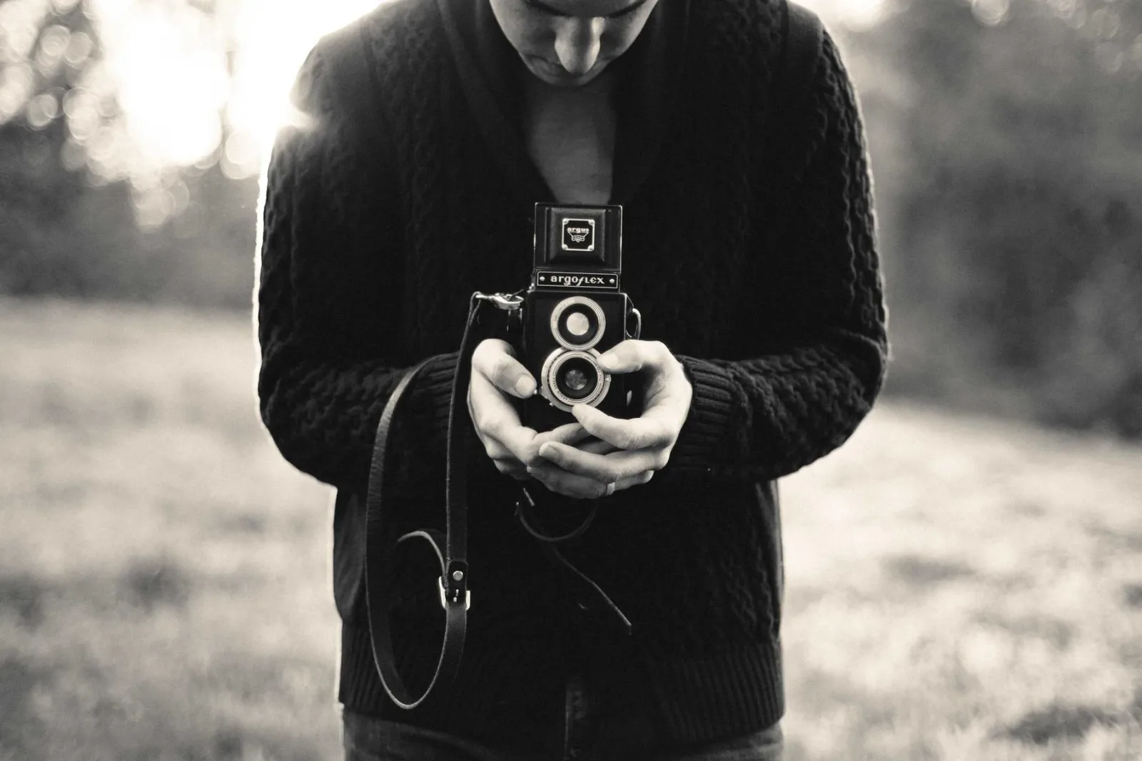 A photographer holding a camera, face obscured behind it