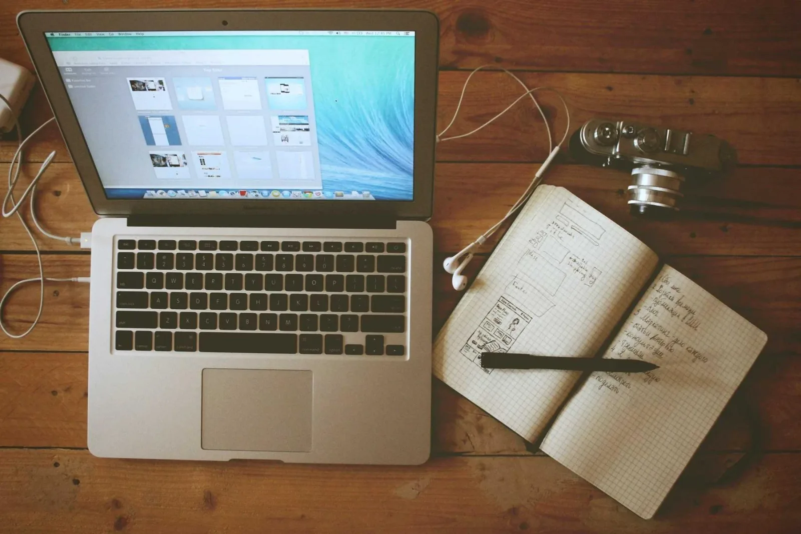 A desk with an open notebook, pen and laptop
